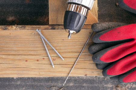 Roofing nails with the drill lie on a wooden beam