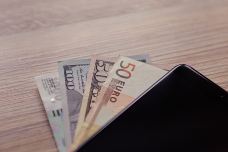 banknotes of different countries lying under the phone (2)の写真素材