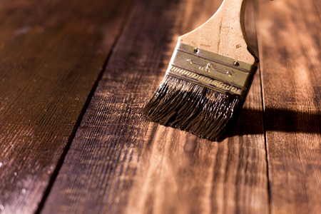 male hand paint wooden surface with brown paint using a paintbrushの写真素材