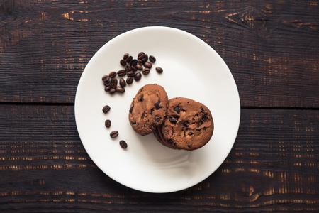 chocolate chip cookies on a white plate with coffee beans on dark wooden tableの写真素材