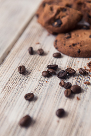 broken chocolate chip cookies with coffee beans on white wooden tableの写真素材