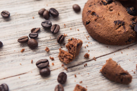 broken chocolate chip cookies with coffee beans on white wooden table