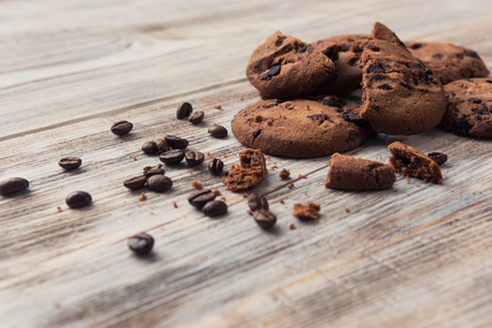 broken chocolate chip cookies with coffee beans on white wooden tableの写真素材