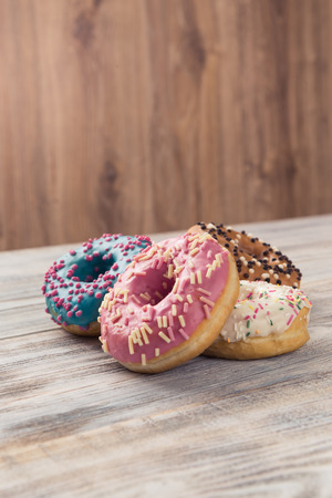 glazed donuts with sprinkles on a white wooden tableの写真素材