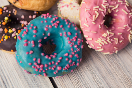 glazed donuts with sprinkles on a white wooden tableの写真素材