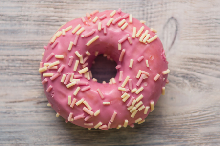glazed donuts with sprinkles on a white wooden tableの写真素材