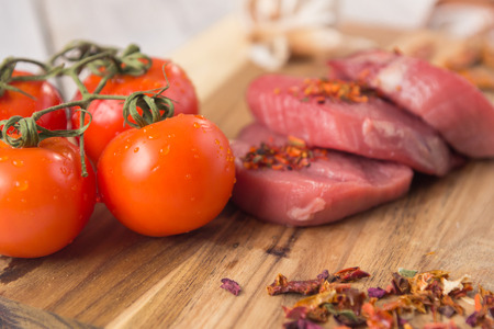 beef steak with vegetables and spices on a cutting Board, a white wooden tableの写真素材