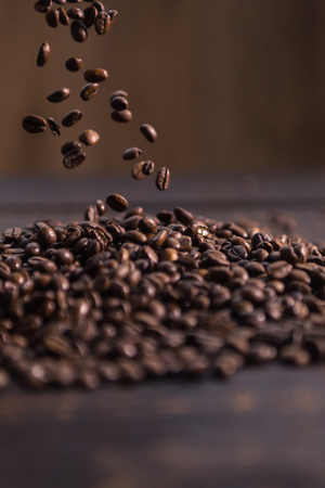 roasted coffee beans fall on dark wooden tableの写真素材