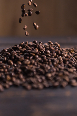 roasted coffee beans fall on dark wooden tableの写真素材