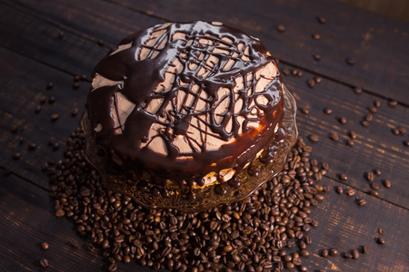 icing biscuit cake soaked in cream on a dark wooden table with roasted coffee beansの写真素材