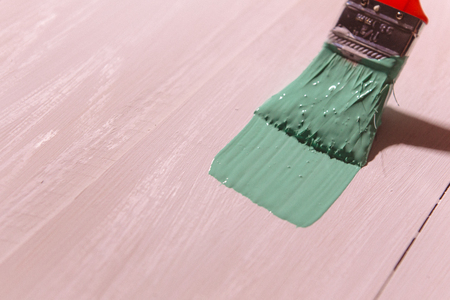 man's hand paint brush with green paint on white wooden tableの写真素材