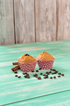 cupcakes with cinnamon sticks and coffee beans on a green wooden backgroundの写真素材