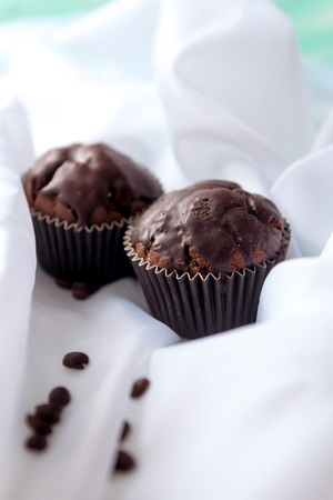 chocolate muffins with coffee beans on white fabricの写真素材