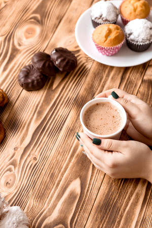 Cup of coffee in female hands on wooden backgroundの写真素材