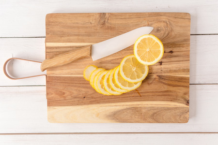 sliced lemon with knife on cutting Board and white wooden tableの写真素材