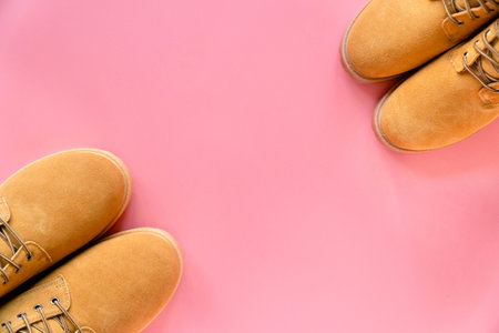 two pairs of yellow winter boots on pink background with a copy space on the centerの写真素材