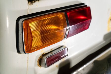rear lantern of an old car with a white rusty bodyの写真素材