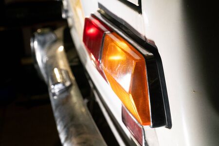 side of the rear headlight or the background and the body of the old white car with a chrome bumperの写真素材