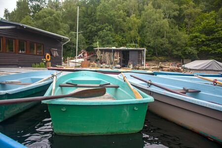 Blue and brown paddle boots on the pier in the canal lake, trees and reflections in the waterの写真素材