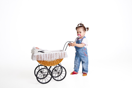 Baby playing with a baby carriage on a white backgroundの写真素材
