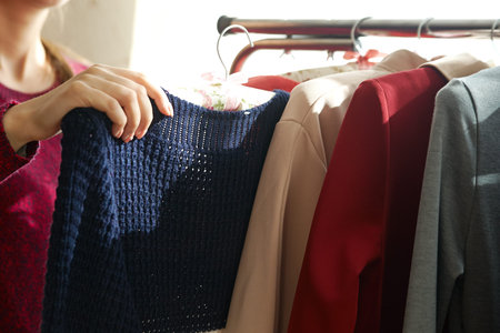 Colorful clothes hanging on a hanger and a female hand holding a dress