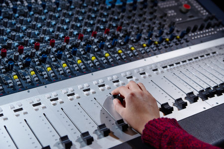 Closeup of hands  working on mixer console, twisting knobs, studio equipment concept