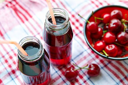Two glass bottles with cherry juice, a cup with a berry, top viewの写真素材