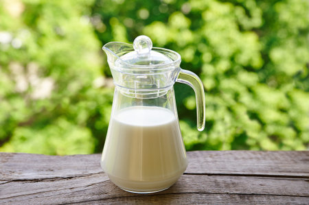 Jug and glass of milk on the wooden table. Nature background.の写真素材