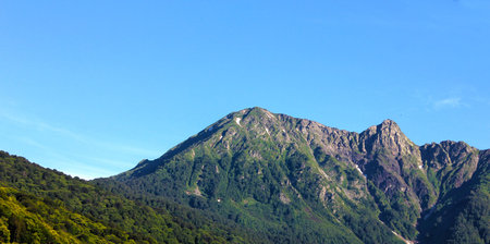 Mountain landscape. Green mountain with a rocky peak against the blue sky.