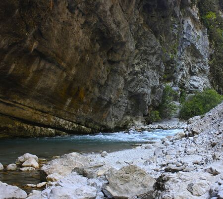 Blue mountain stream among rocks and stones near the cliffの写真素材