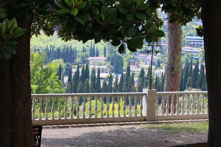 Alley with a railing and a lantern with a view of the village of Novy Afon among trees and foliage.の写真素材