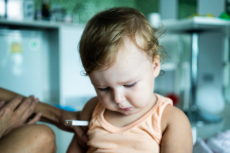 The child put a thermometer. Temperature measurement. The child pulls the thermometerの写真素材