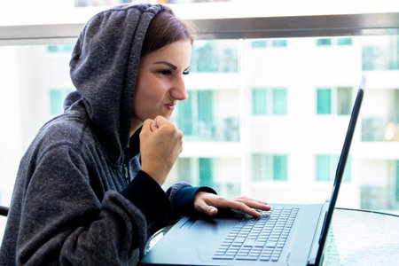 Woman Hacker programmer is working on computer in cyber security center filled with display screens.