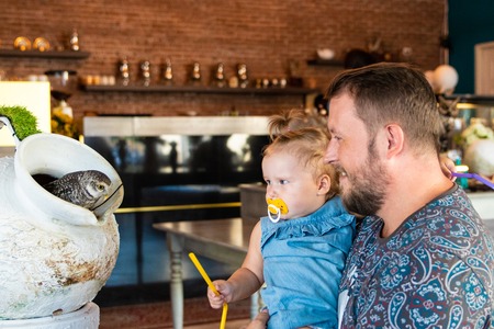 dad shows the baby an owl. baby strokes an owl.の写真素材