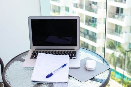 Work office desk with a computer laptop, notebook, pen on the glass tableの写真素材