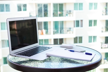 Work office desk with a computer laptop, notebook, pen on the glass tableの写真素材