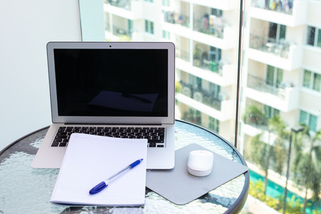 Work office desk with a computer laptop, notebook, pen on the glass tableの写真素材