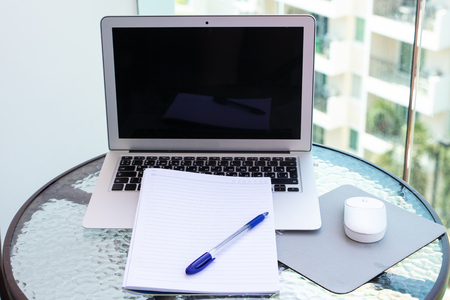 Work office desk with a computer laptop, notebook, pen on the glass tableの写真素材