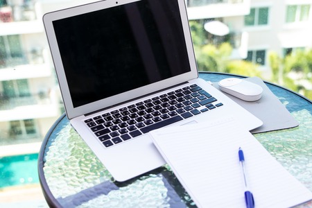 Work office desk with a computer laptop, notebook, pen on the glass tableの写真素材