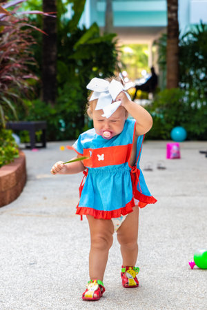 a girl in a blue dress with a white bow is surprised, rejoices, screams, cries, raises her hands. childrens fashion conceptの写真素材