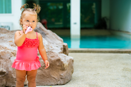 a girl in a bathing suit with white beads is surprised, rejoices, shouts, raises her hands. childrens fashion conceptの写真素材