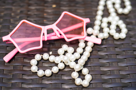 background image of sunglasses and white pearl beads on wooden.の写真素材