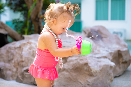 a girl in a bathing suit with white beads is surprised, rejoices, shouts, raises her hands. childrens fashion conceptの写真素材