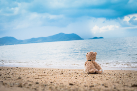 Teddy bear sit alone at the seashore.の写真素材