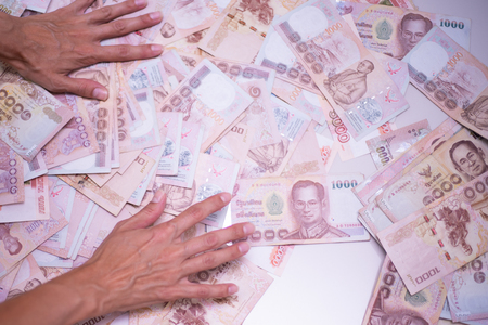 female hands collect a lot of money on a white table, Thai banknotesの写真素材