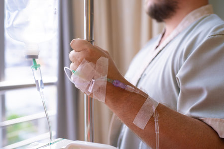 Close-up. patient with a dropper looks out the window of the hospital room and smiles. back view....