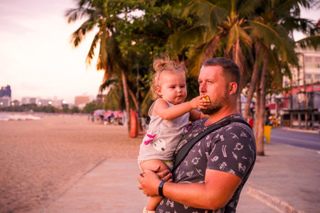 Father and little daughter on beach at sunset