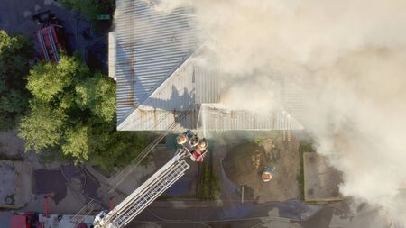 Burning roof of a residential high-rise building, clouds of smoke from the fire. firefighters extinguish the fire. top view.の写真素材