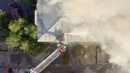 Burning roof of a residential high-rise building, clouds of smoke from the fire. firefighters extinguish the fire. top view.の素材 [FY310127538890]