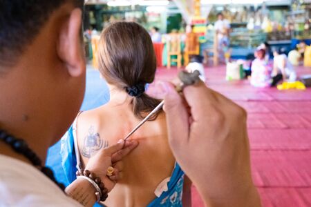 yantra tattoo or sak yant, thai sacred tattoo. master draws a girl colorless tattoo Sak Yant with a special oil. Thailandの写真素材